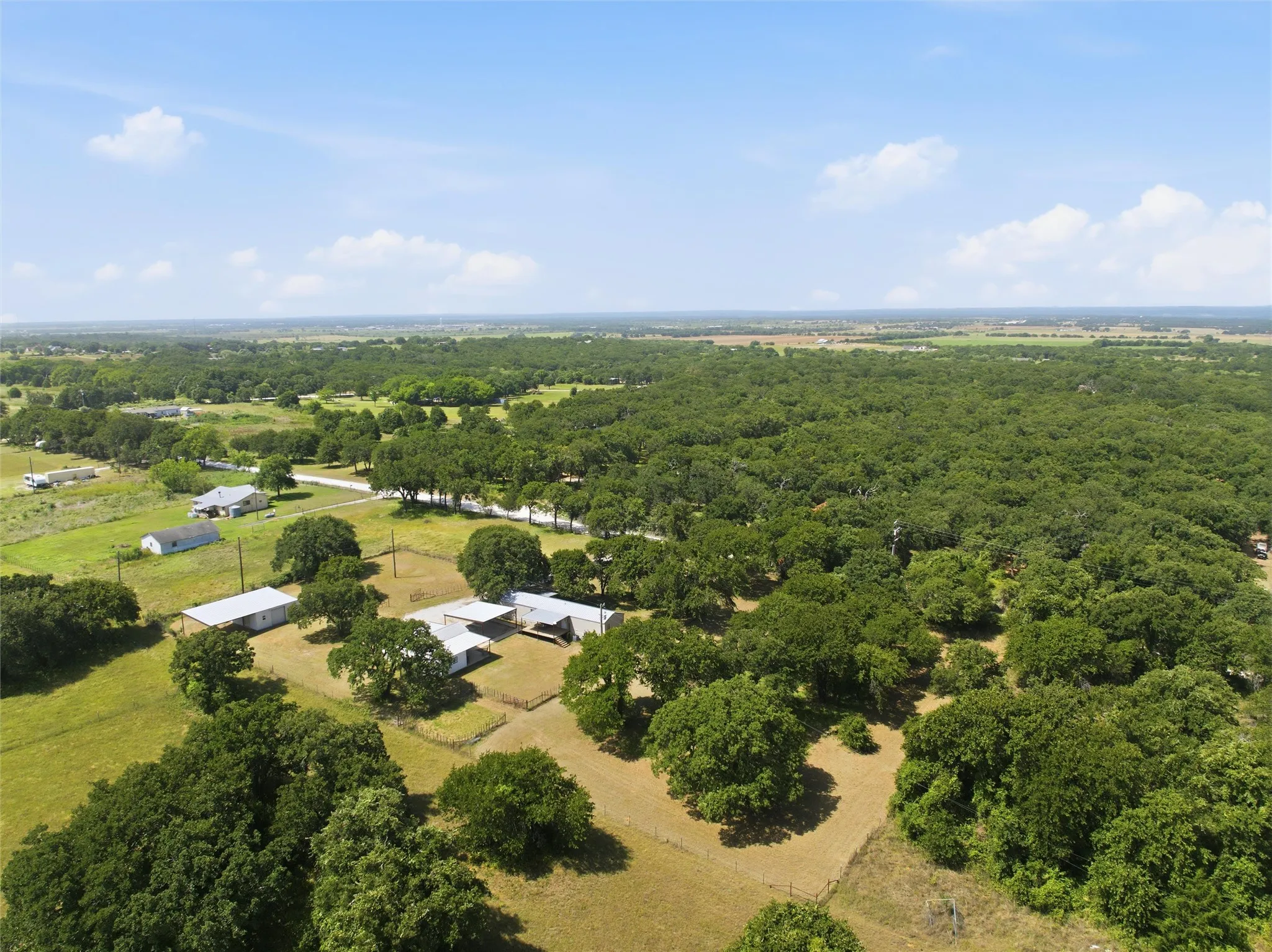 Expansive acreage featuring multiple structures, mature trees, and open pastures