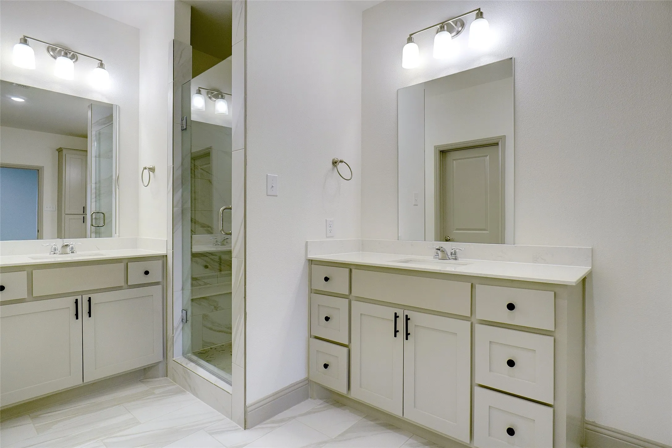 Bathroom featuring dual vanities with light cabinetry, undermount sinks, and light countertops