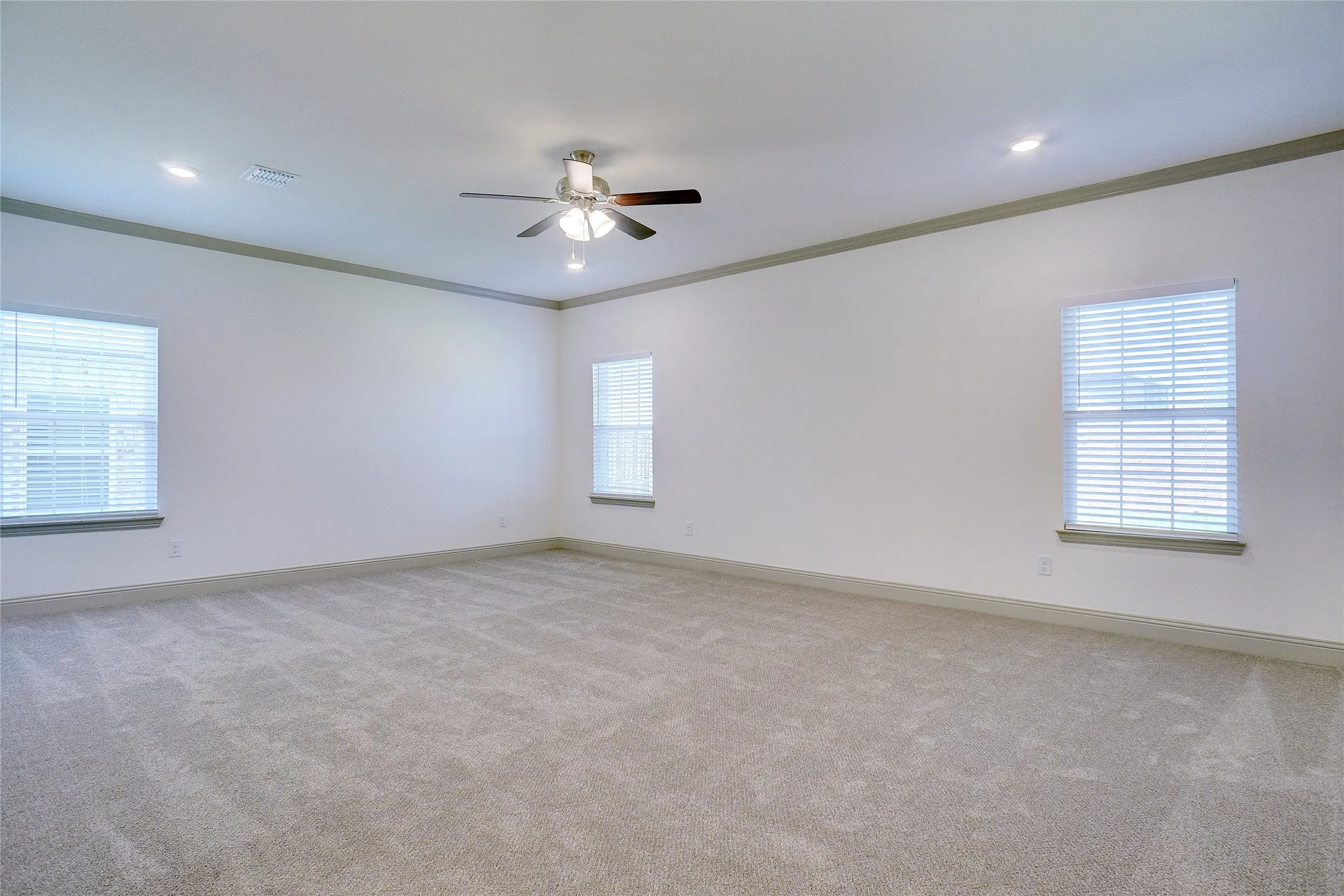 Spacious room featuring neutral carpeting, white walls, and elegant crown molding