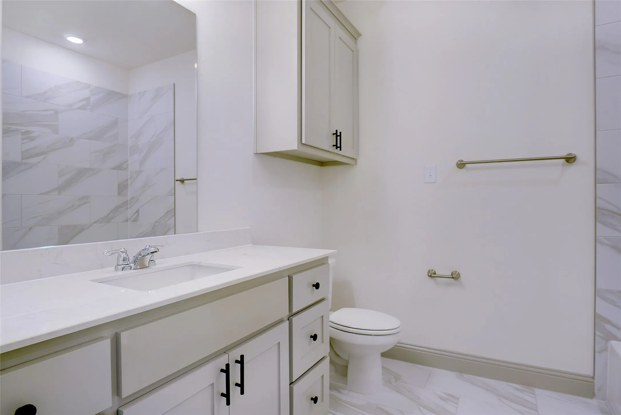 Bathroom featuring a vanity with an integrated sink, polished chrome faucet, and light-toned countertop