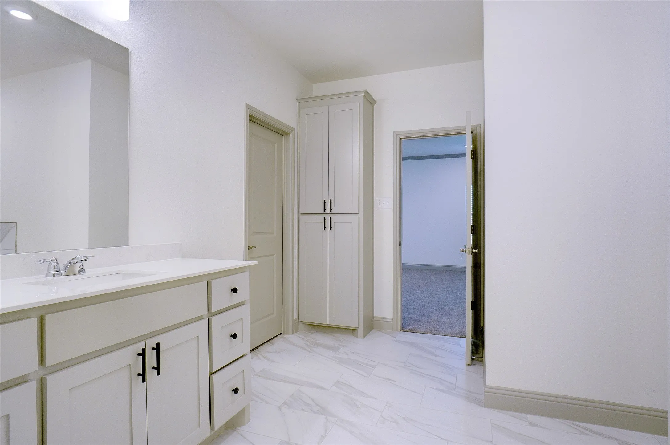 White vanity with an integrated sink and chrome faucet, featuring a white countertop and black hardware