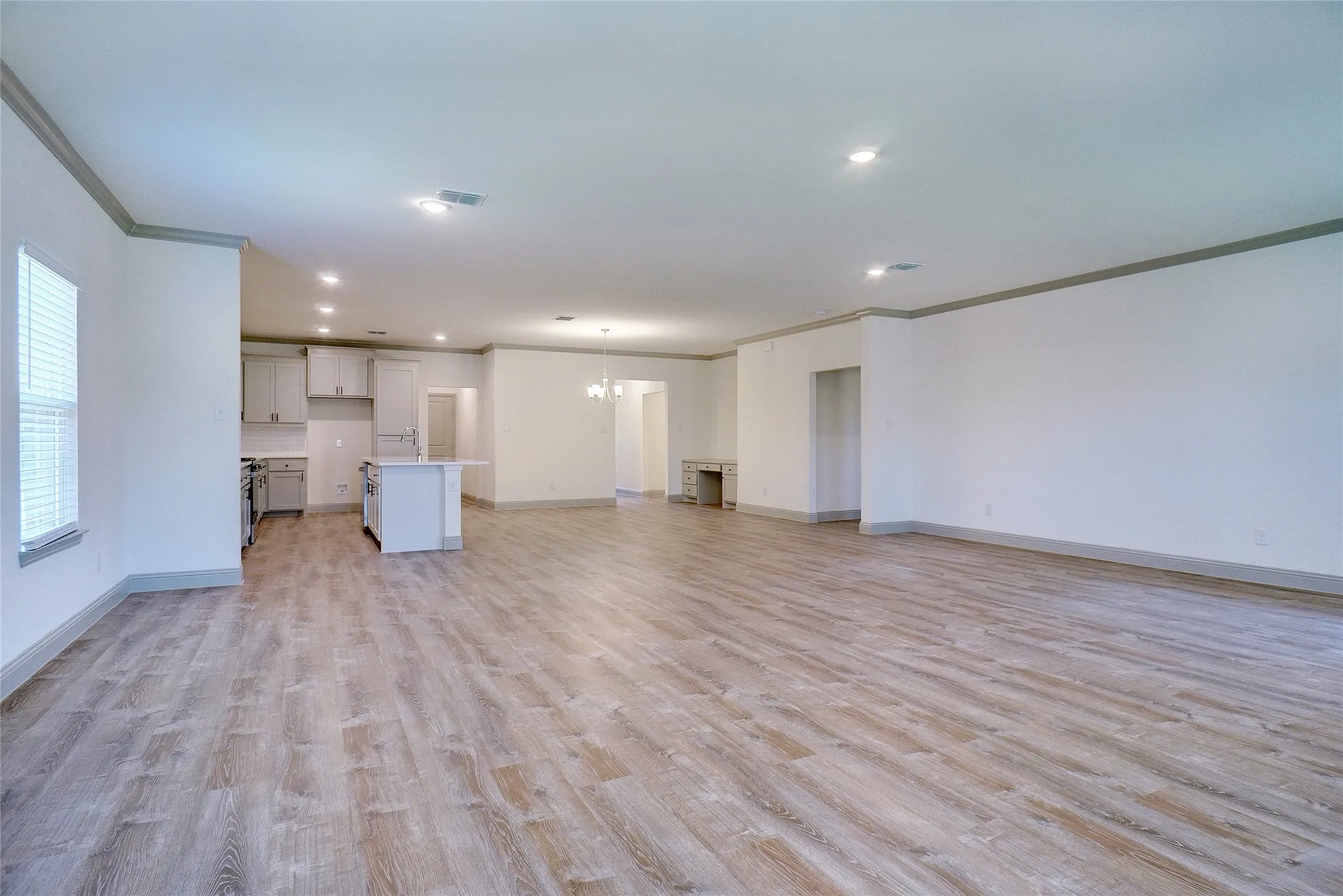Expansive open-concept living space featuring wood-finish flooring, recessed lighting, and crown molding