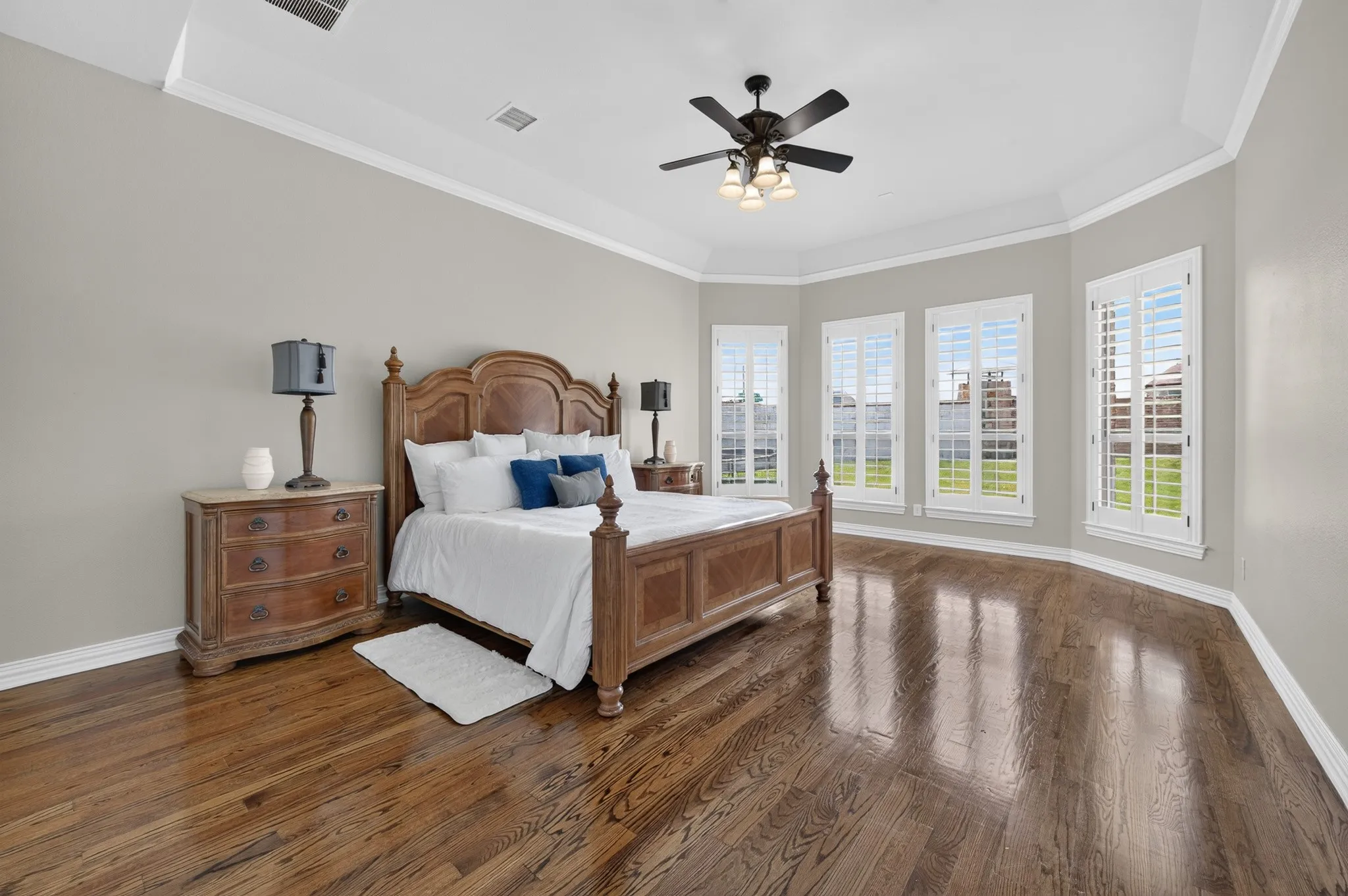 Large, private primary bedroom located in the rear of the home.  Take note of the ample wood flooring, Wall of windows for natural light to flow in, crown molding and ceiling fan!