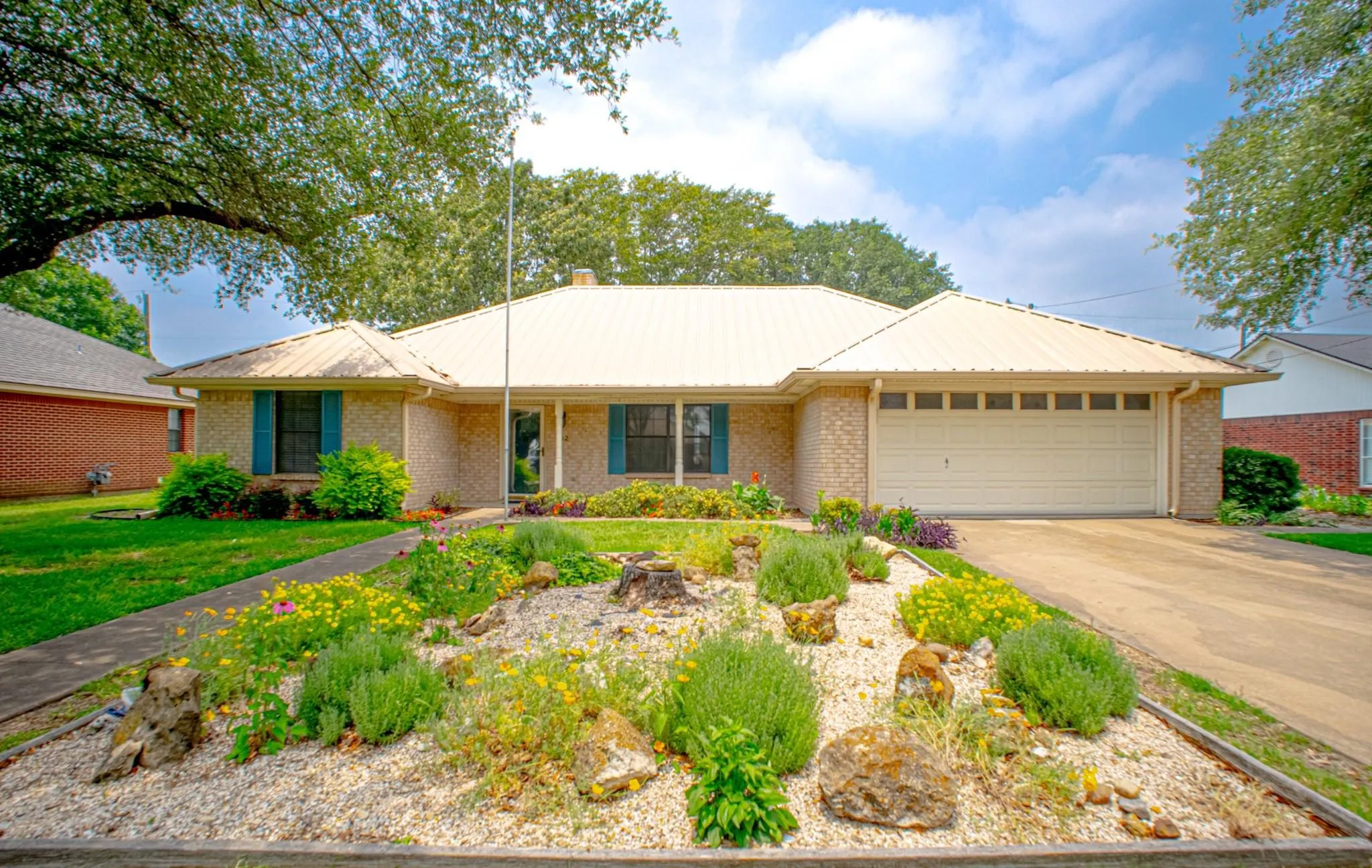 Single-story residence featuring a metal roof, brick exterior, and attached two-car garage