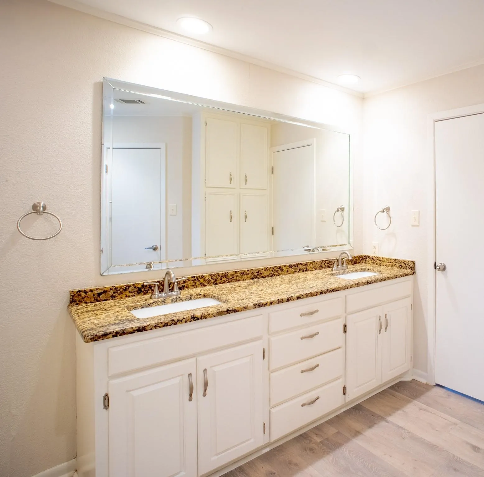 Double vanity with white cabinetry, integrated sinks, and patterned granite countertop