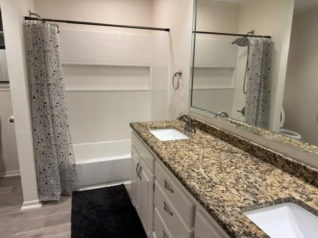Bathroom featuring a double vanity with stone-finish countertop, dual sinks, and white cabinetry