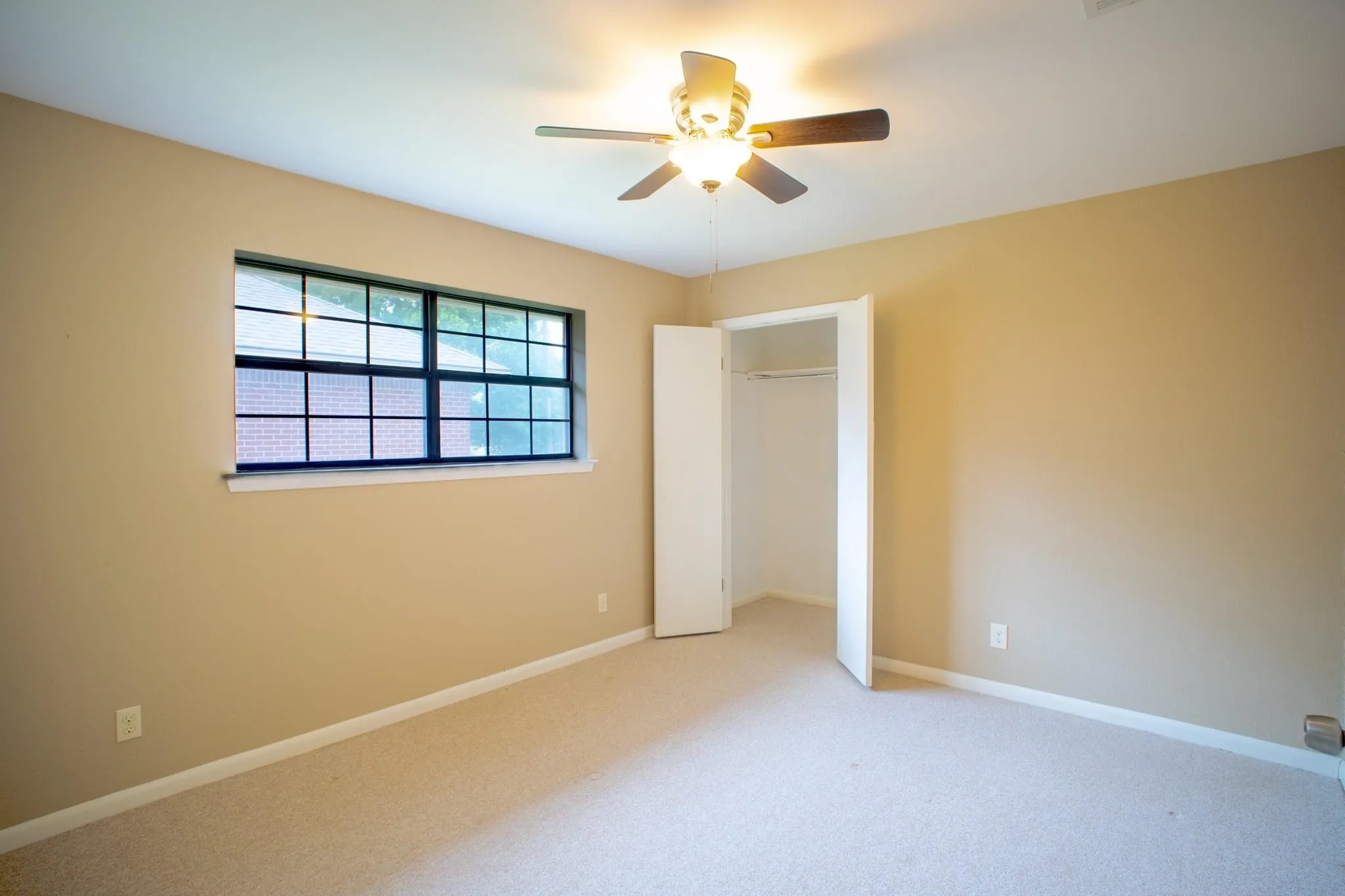 Neutral-toned carpeting and walls complement a multi-pane window with dark framing