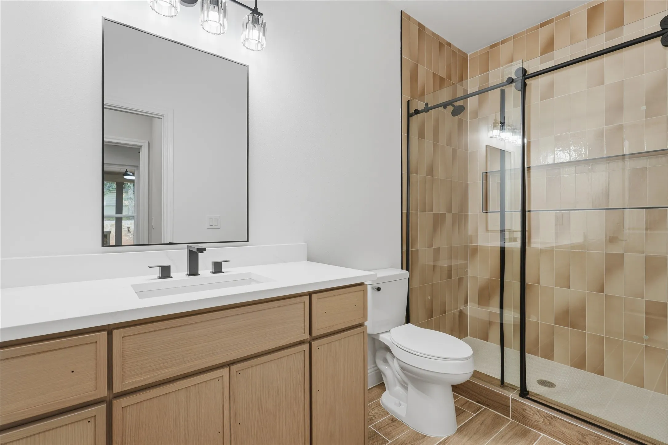 Bathroom featuring a light wood-finish vanity with a white countertop, an undermount sink, and a matte black faucet