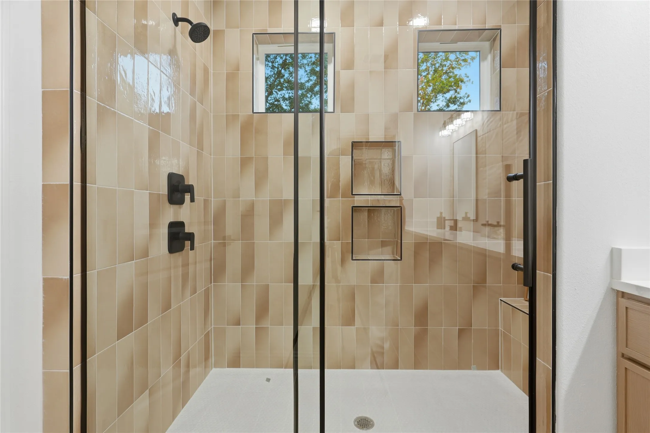 Walk-in shower featuring a matte black rain shower head, vertical stacked tile, and dual built-in shower niches