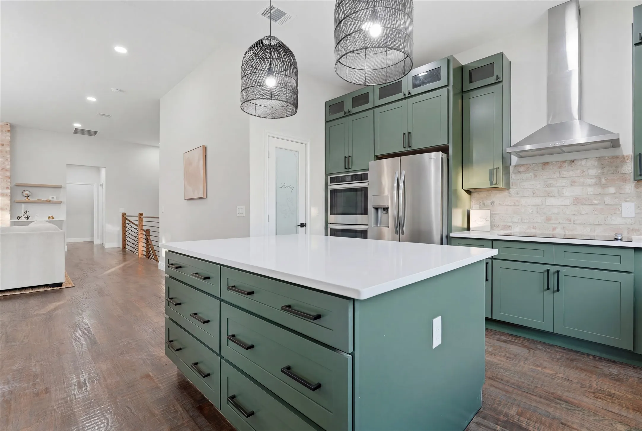 Kitchen island featuring a white countertop and deep green cabinetry with black hardware