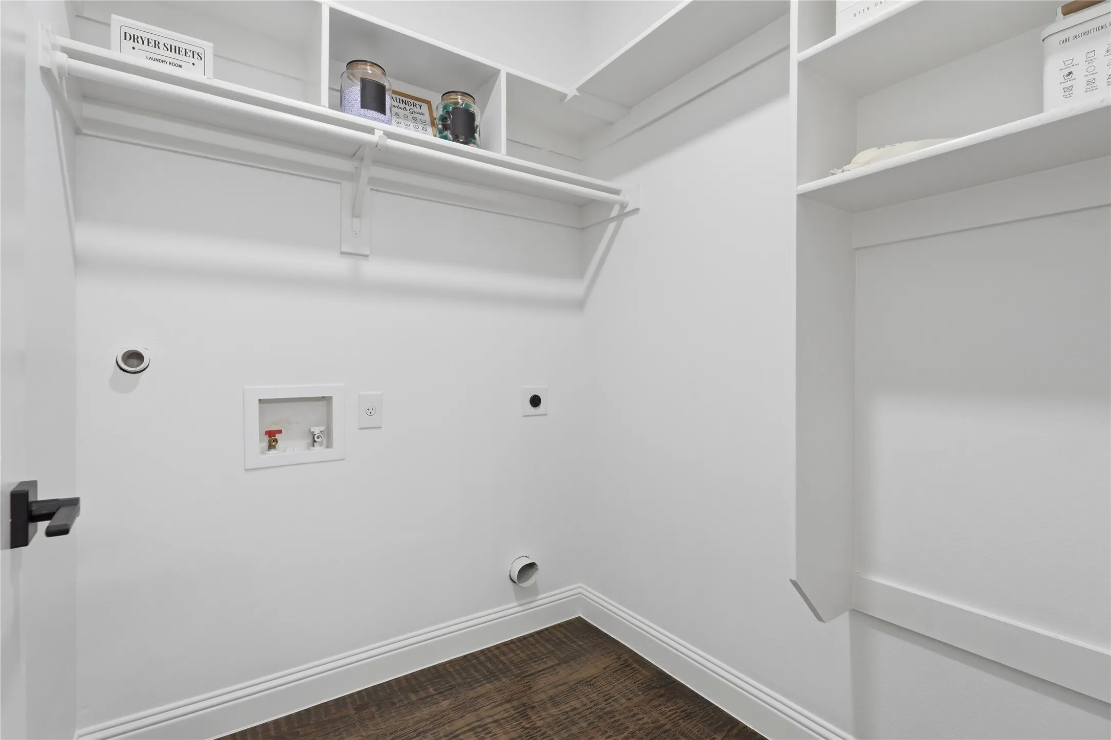 Laundry area featuring wood-finish flooring, white walls, and built-in shelving
