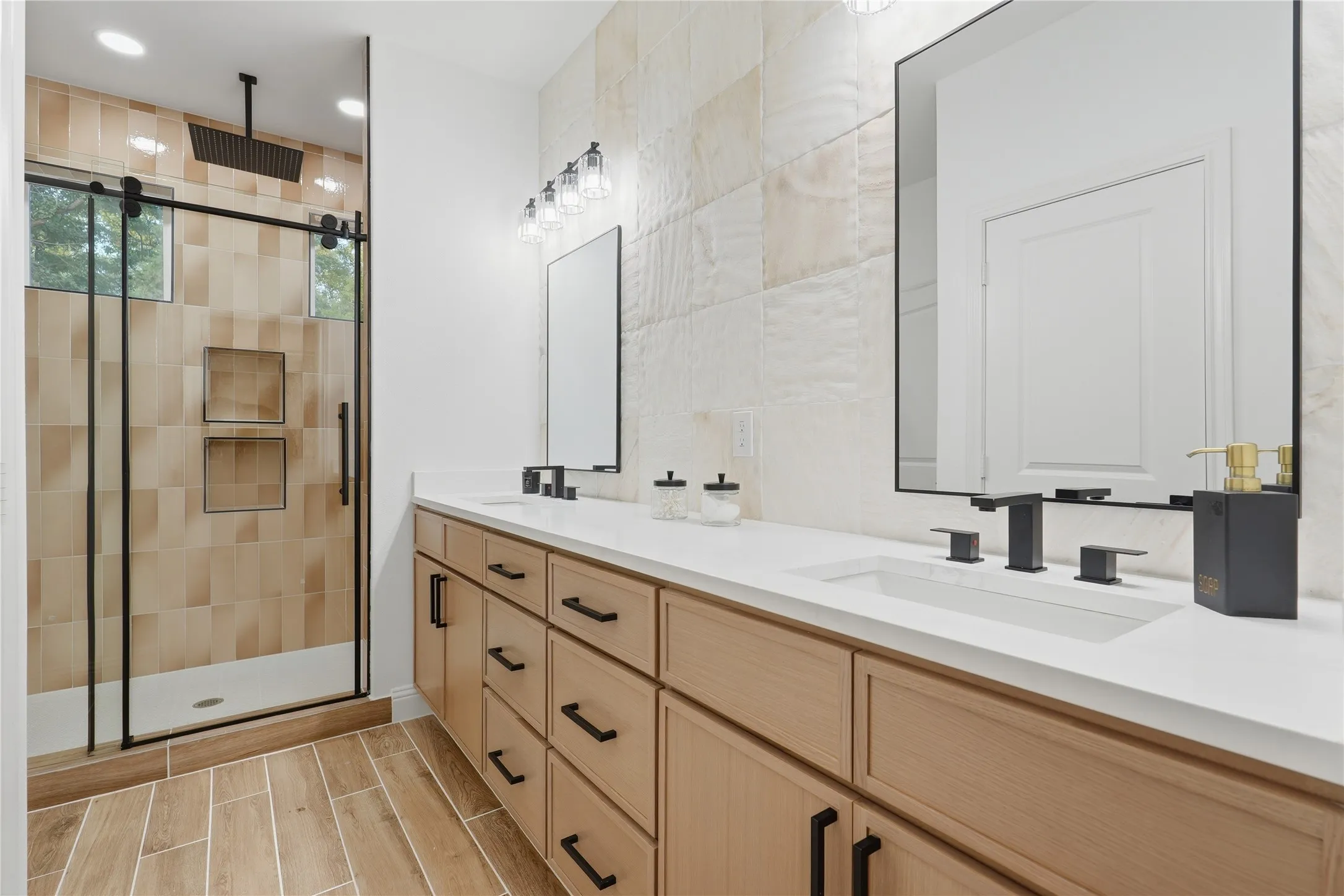 Bathroom featuring a dual vanity with light wood-finish cabinetry and black hardware