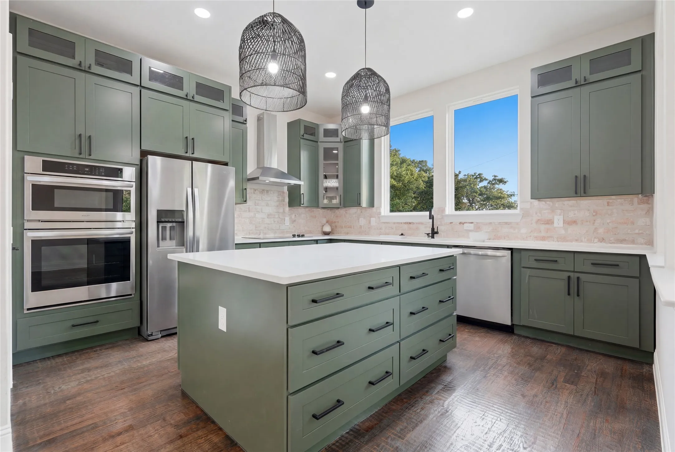 Modern kitchen featuring a large central island with a white countertop and olive green cabinetry