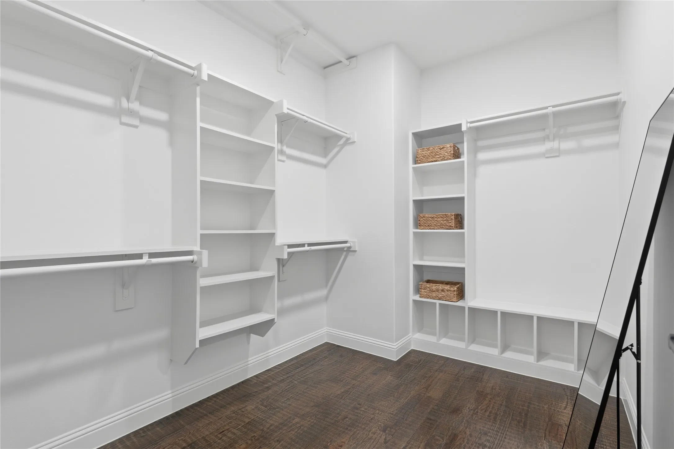 Walk-in closet featuring extensive built-in shelving, multiple hanging rods, and wood-finish flooring