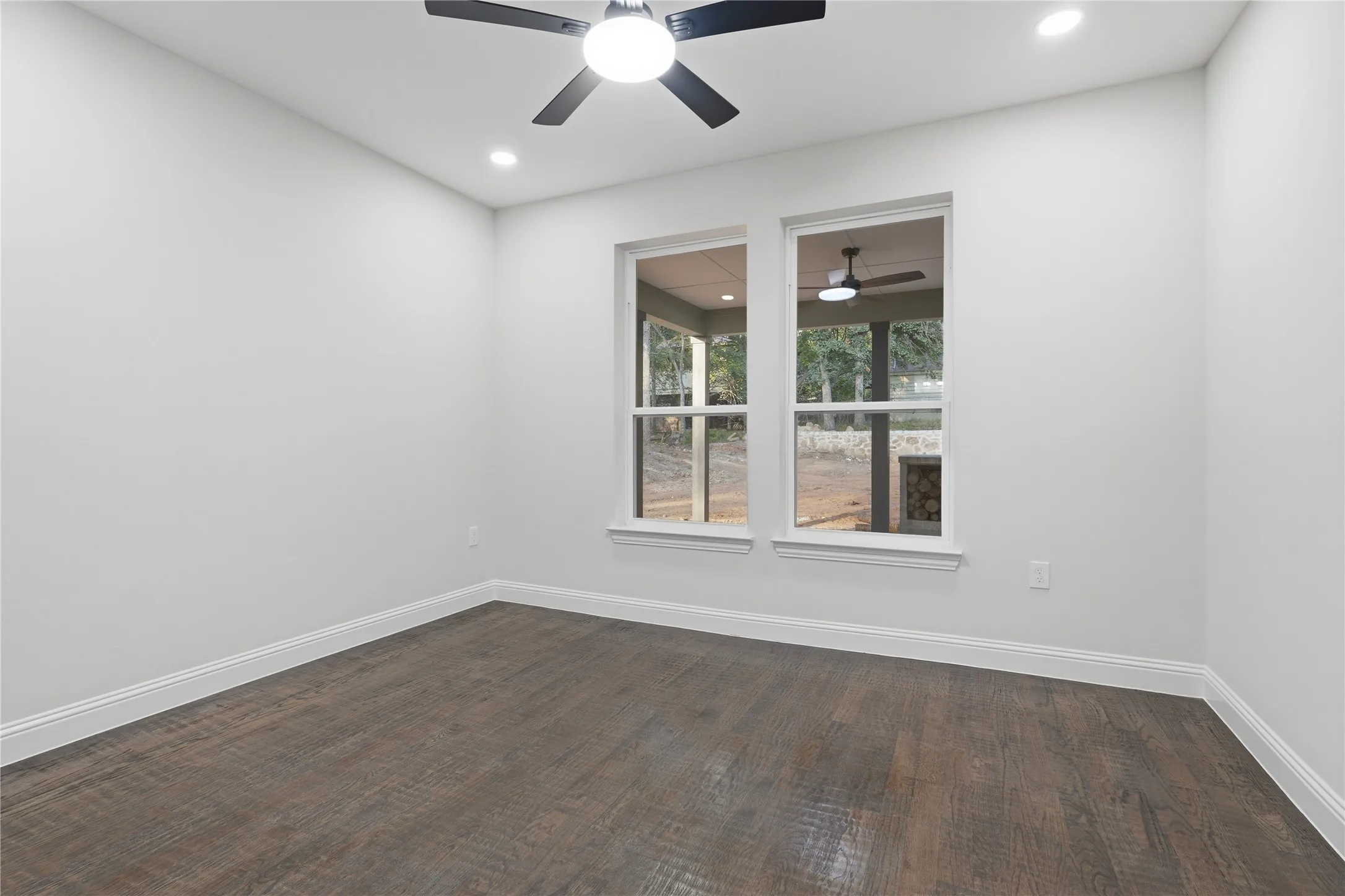 Bright interior space featuring two large windows, wood-finish flooring, recessed lighting, a ceiling fan, and white baseboards