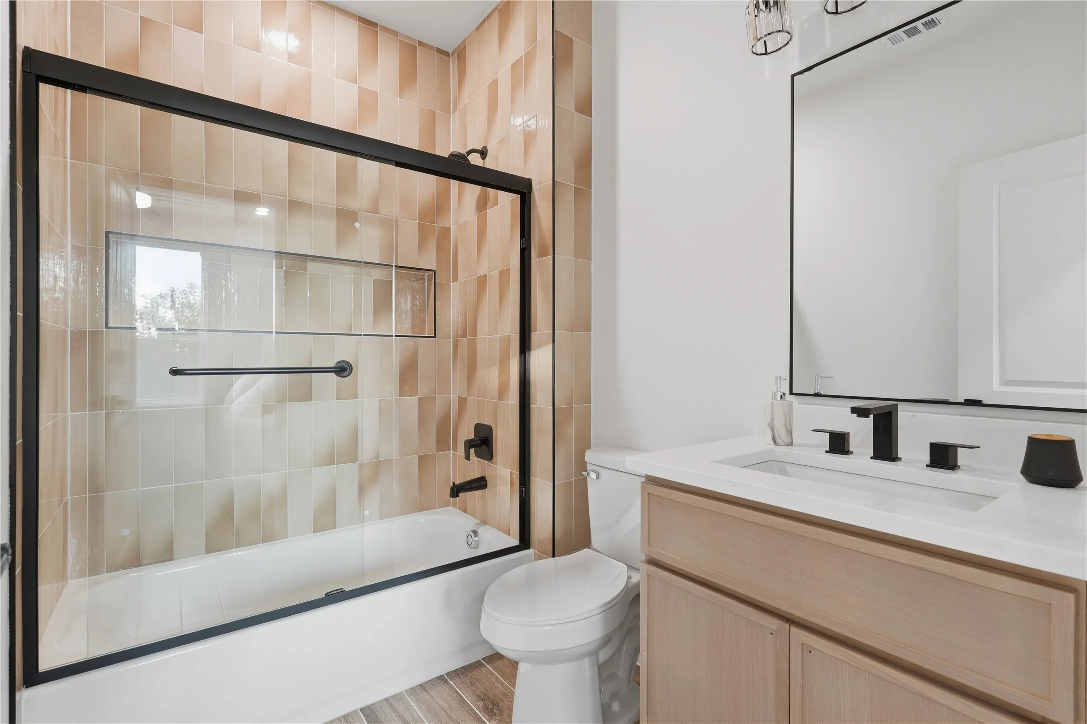 Bathroom featuring a tiled shower/tub combination with a clear glass enclosure and matte black fixtures