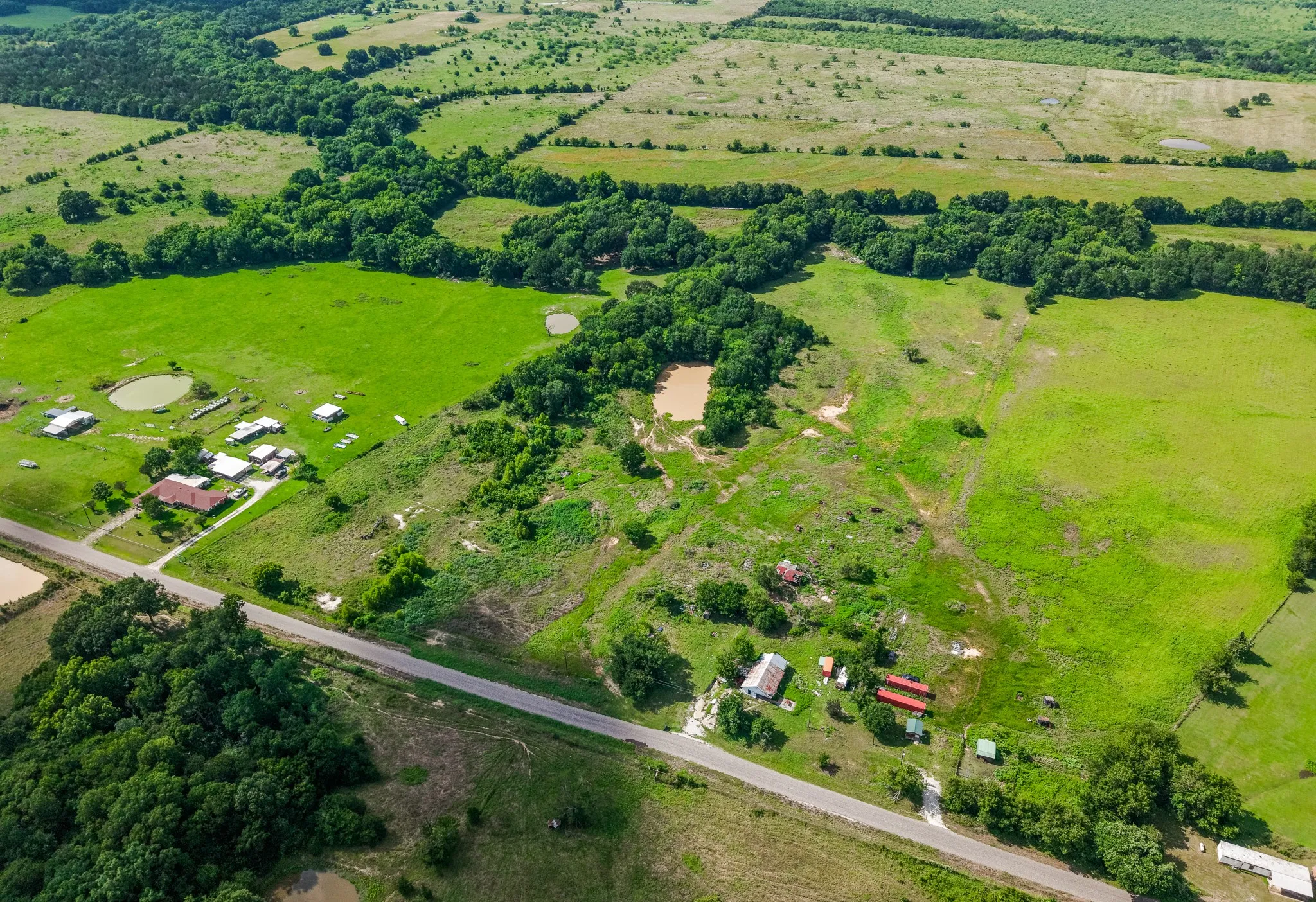 Expansive rural landscape featuring multiple clearings, scattered trees, and two visible ponds
