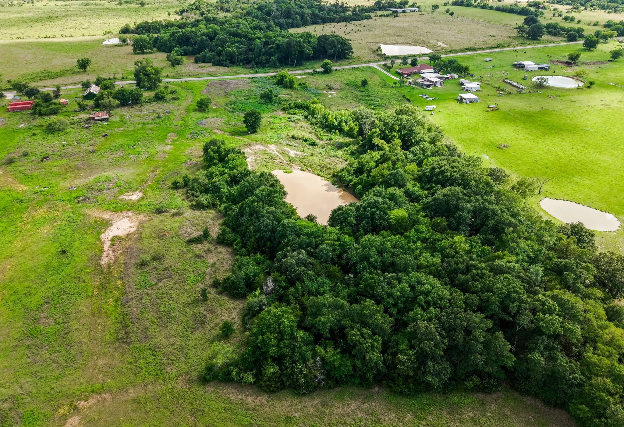 Expansive acreage featuring mature trees, two distinct ponds, and open green fields