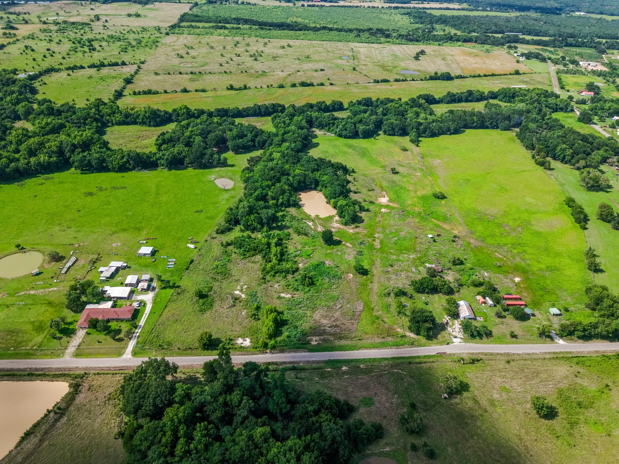 Expansive rural acreage featuring multiple fields, wooded areas, and two visible ponds