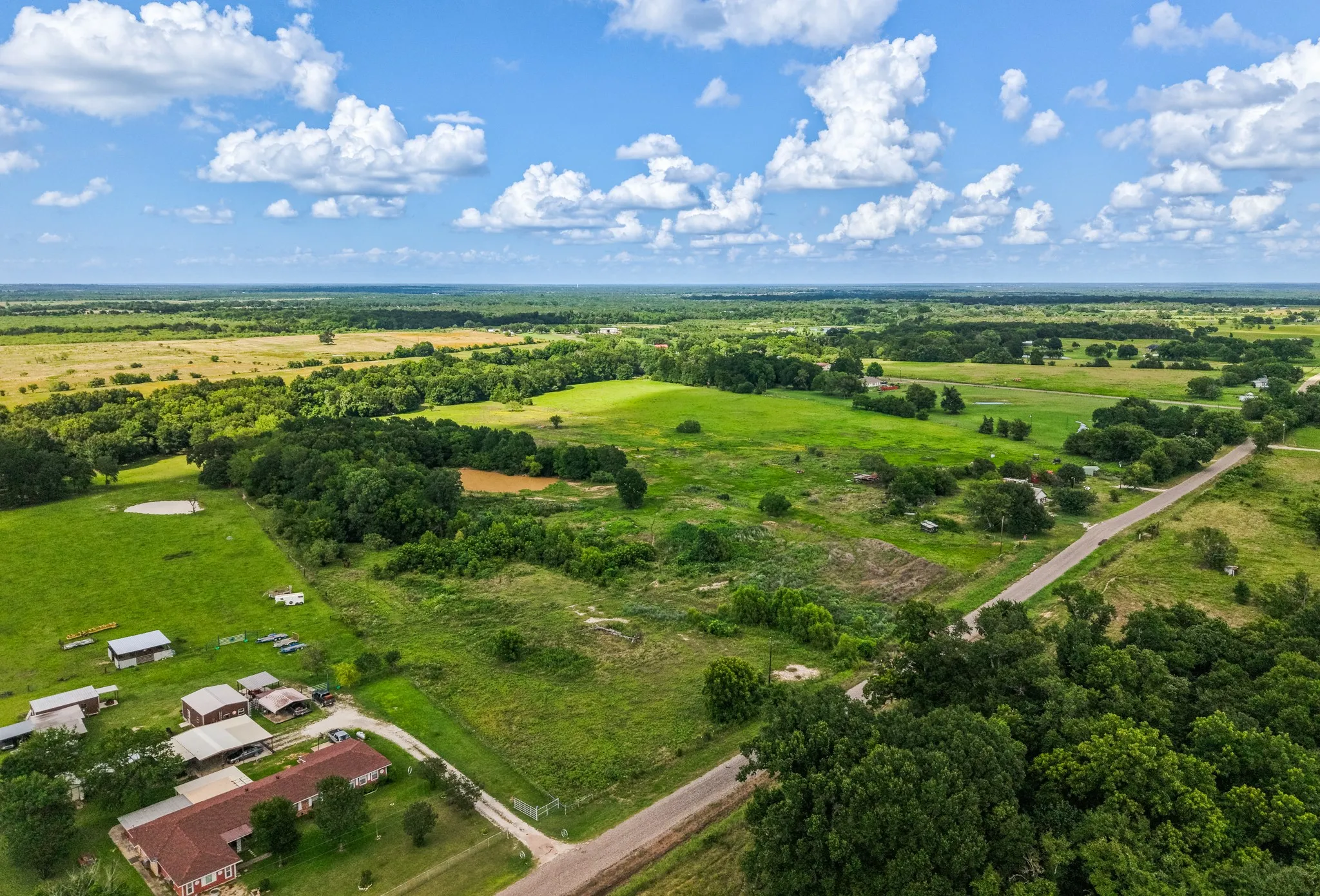 Expansive rural landscape featuring extensive green acreage and a mix of wooded areas