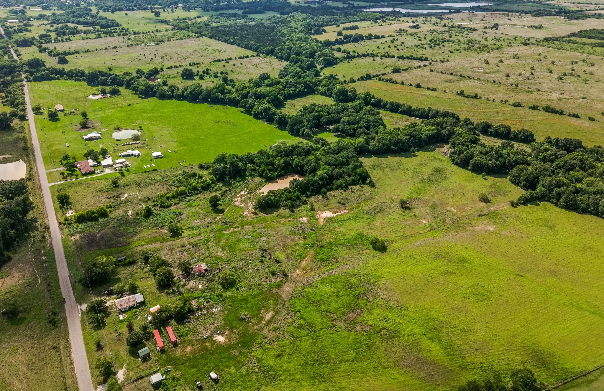 Expansive green pastures featuring scattered trees and a natural water feature