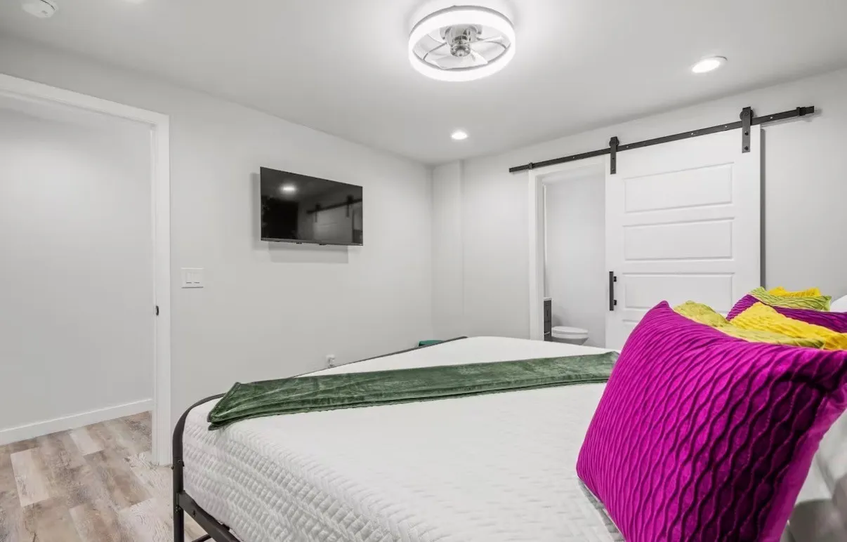 Bedroom featuring light wood-finish flooring, a contemporary ceiling fan, recessed lighting, and a modern barn door