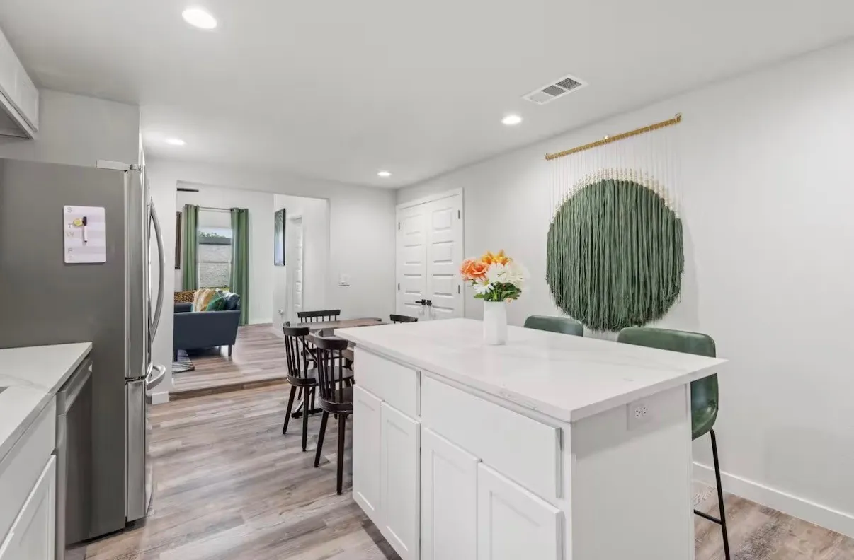 Open-concept kitchen featuring an island with a light-toned countertop, white cabinetry, recessed lighting, and wood-finish flooring