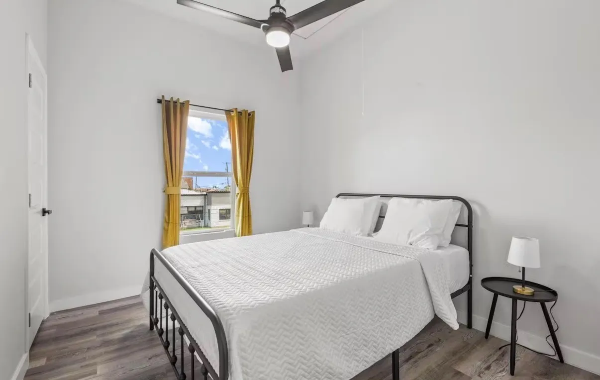 Room featuring wood-finish flooring, a contemporary ceiling fan, and a single window with curtain rods