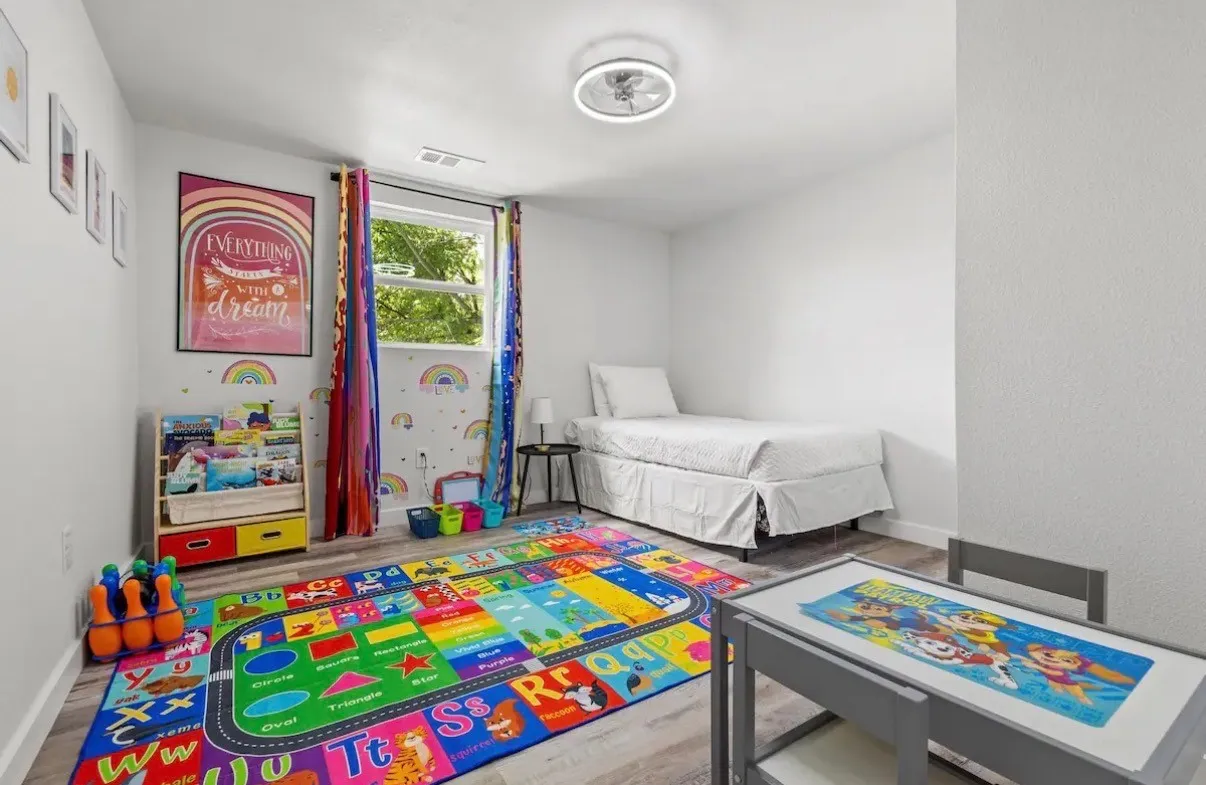 Bright room featuring wood-finish flooring, a window with colorful drapes, and a contemporary ceiling light fixture