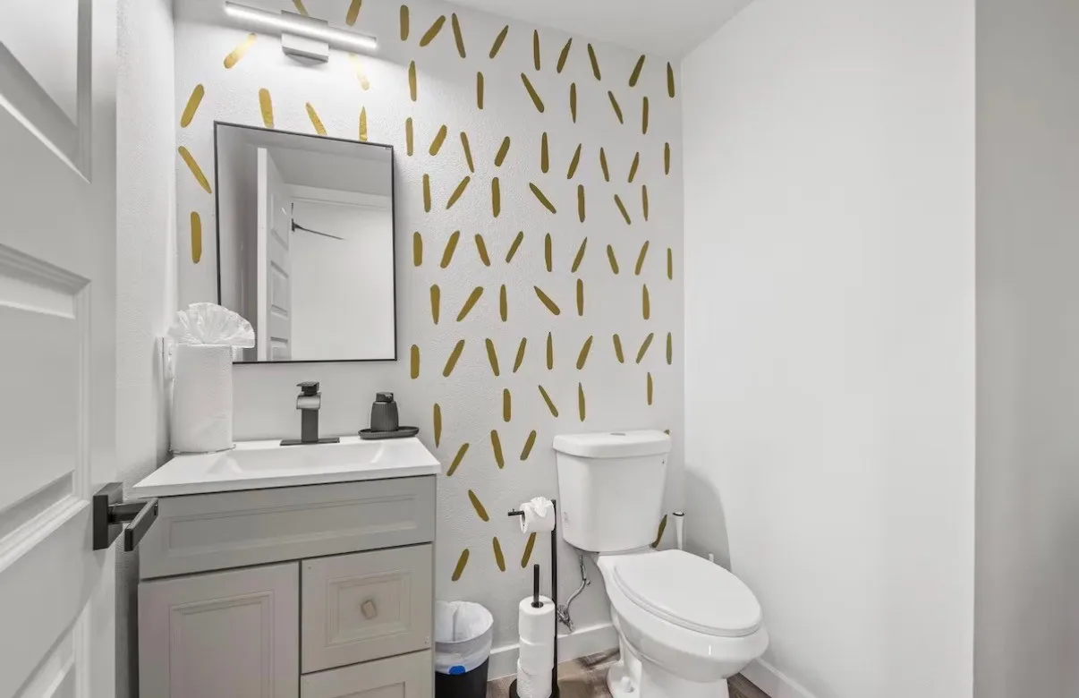 Powder room featuring a vanity with a white countertop and gray cabinetry, a rectangular mirror, and a wall-mounted light fixture