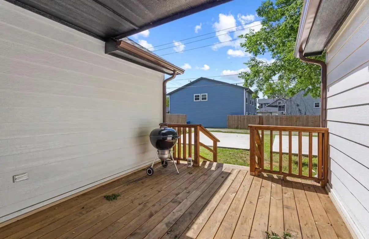 Covered wood-finish deck with wooden railings, providing an outdoor living area