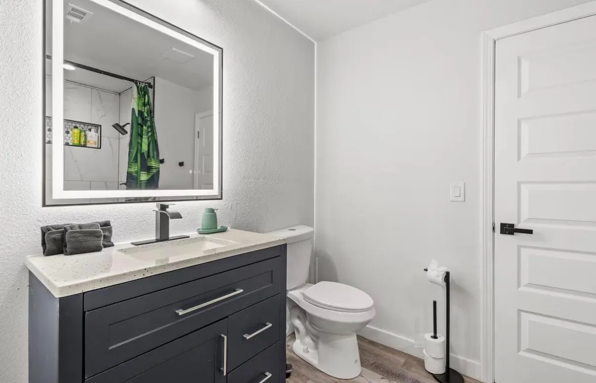 Modern bathroom vanity featuring a dark gray cabinet, integrated sink, and light speckled countertop