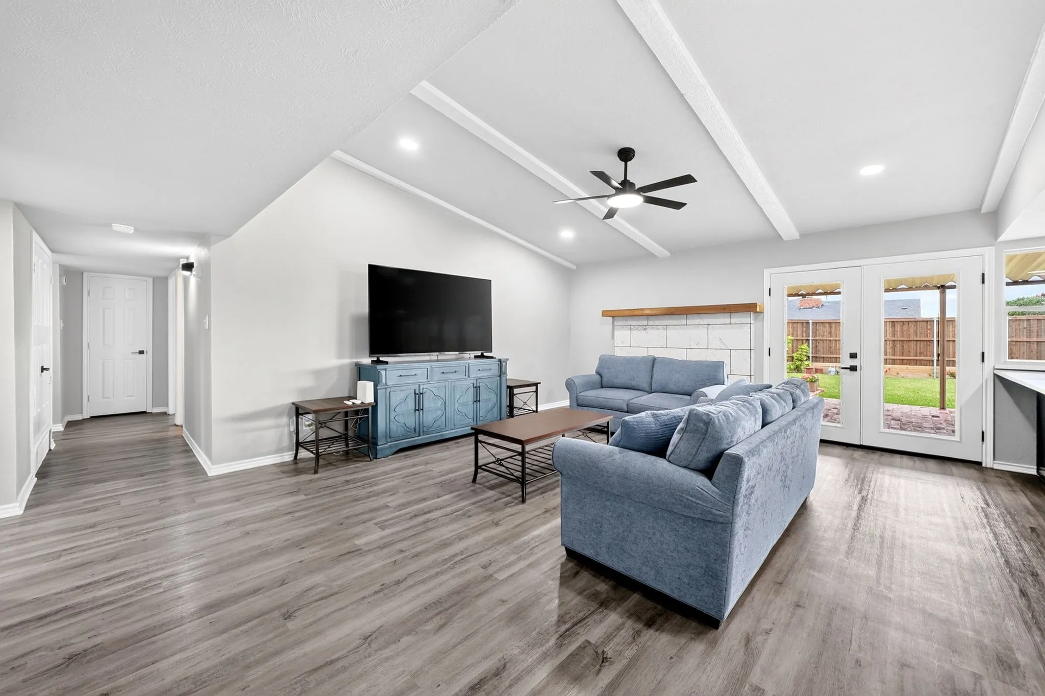 Vaulted ceiling with white wood beams, recessed lighting, and a modern ceiling fan