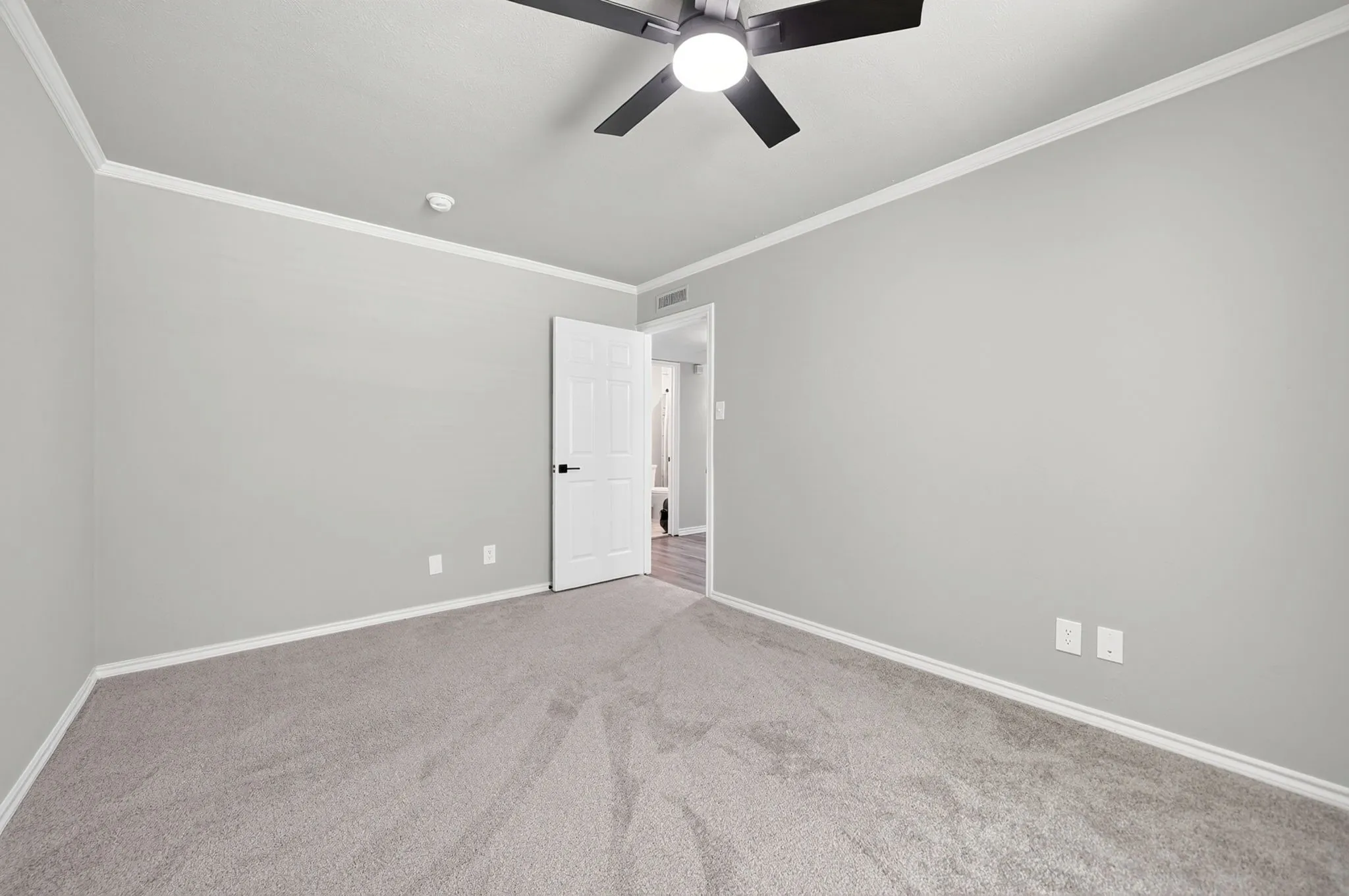 Spacious room featuring light gray walls, white crown molding, and plush gray carpeting