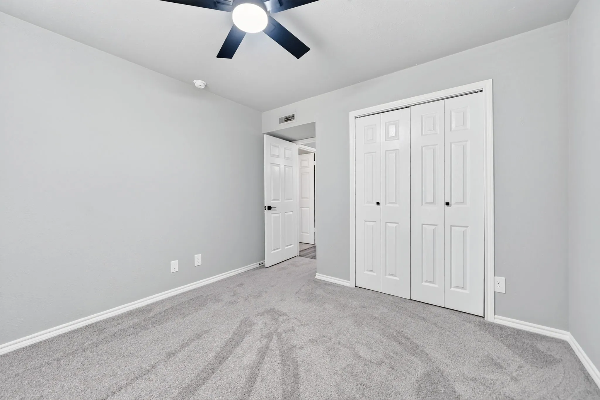 Neutral gray walls and gray carpeting with white baseboards throughout