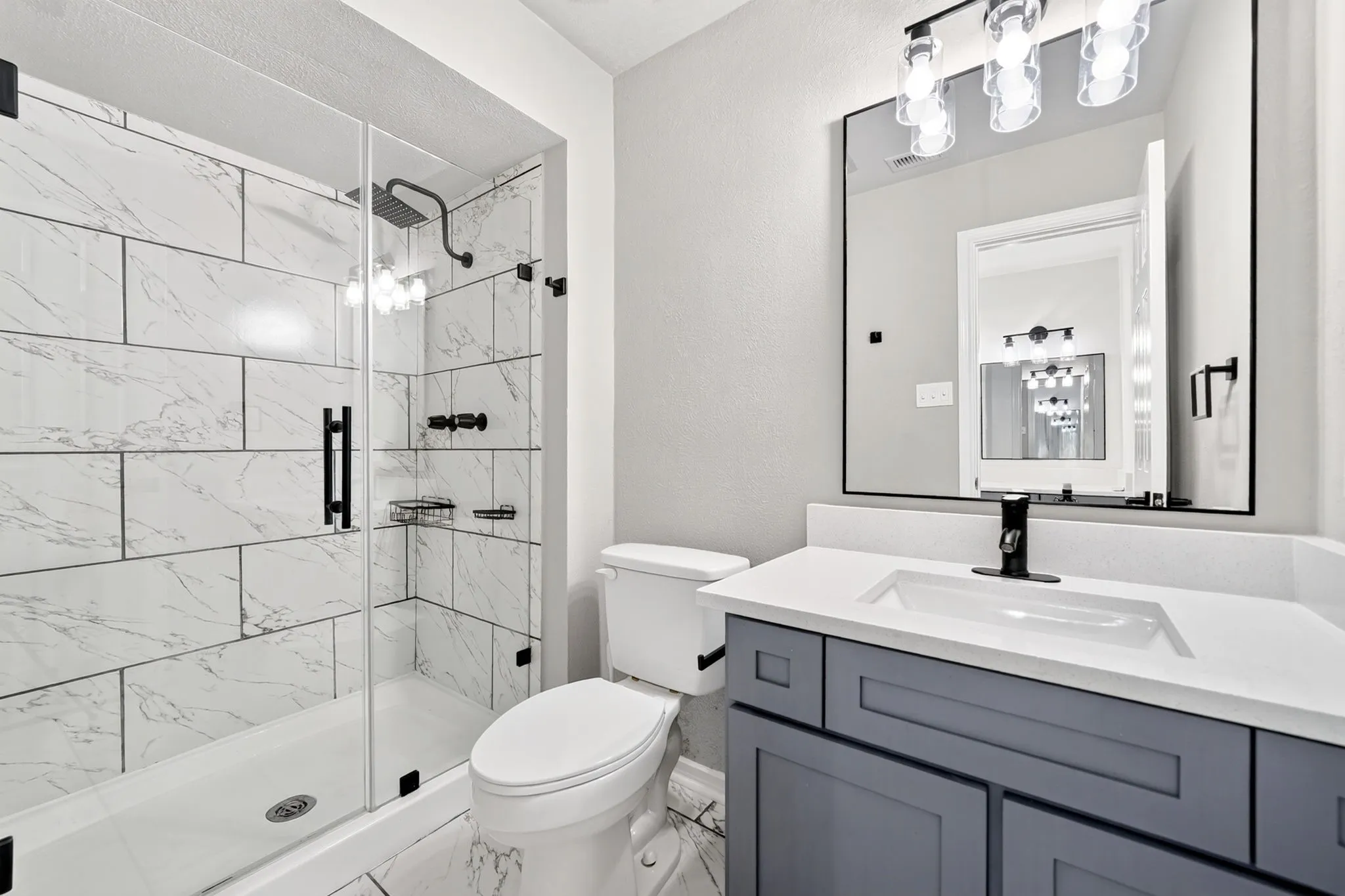 Modern bathroom featuring a glass-enclosed shower with white subway tile, rain showerhead, and matte black fixtures