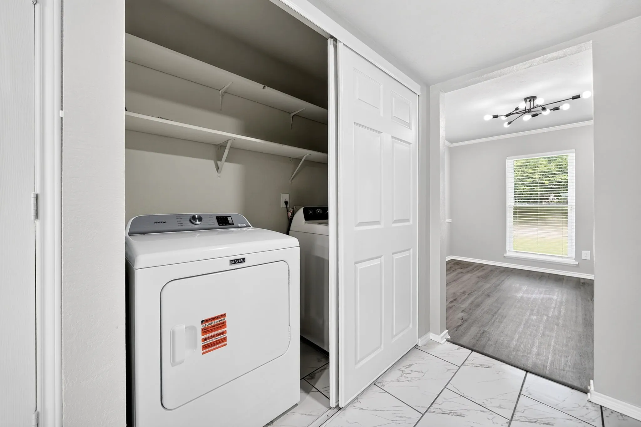 Laundry closet featuring a white dryer and stacked shelving