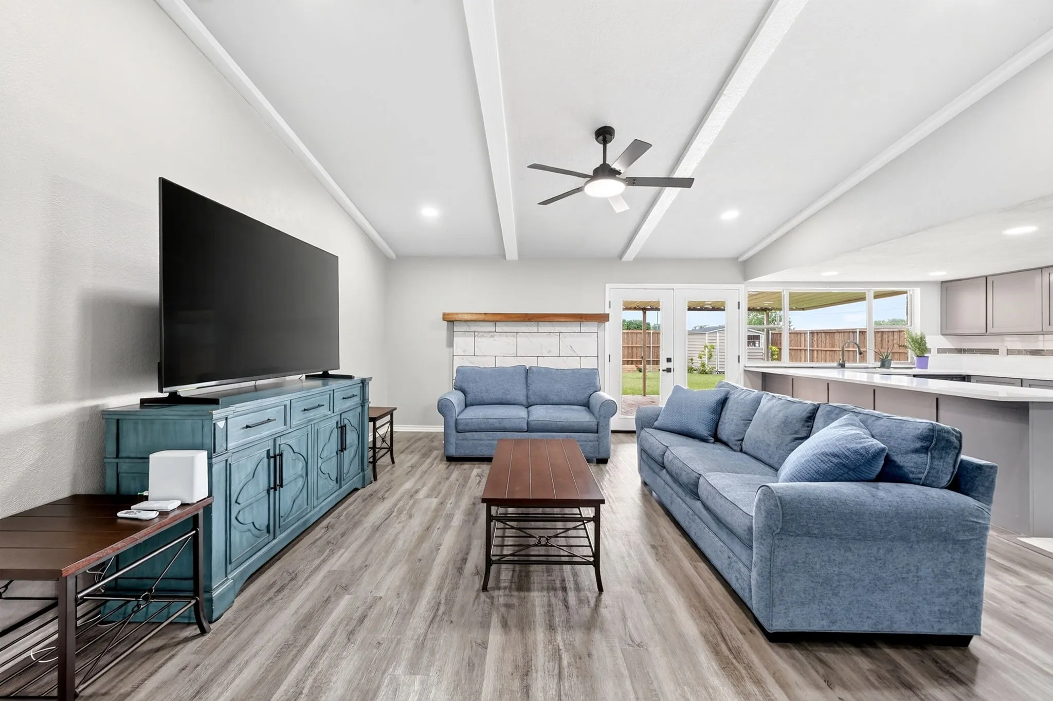 Open-concept living area featuring wood-finish flooring, vaulted ceilings with exposed beams, a ceiling fan, and recessed lighting