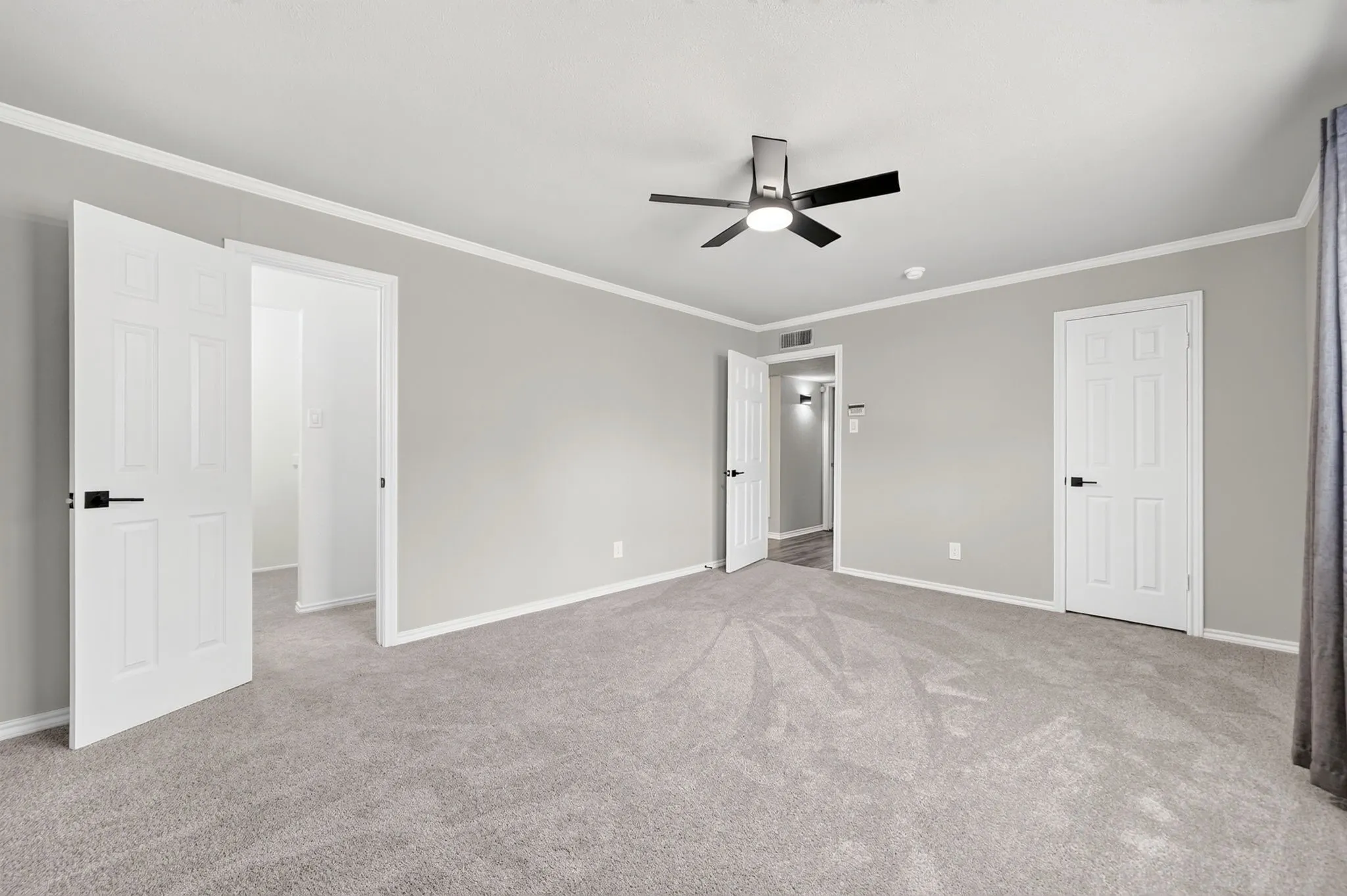 Spacious room featuring light gray walls, white trim, and light gray carpeting