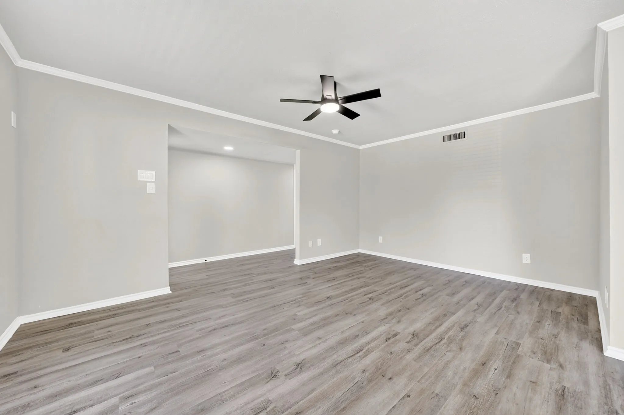 Spacious interior featuring wood-finish flooring, light grey wall paint, and white crown molding