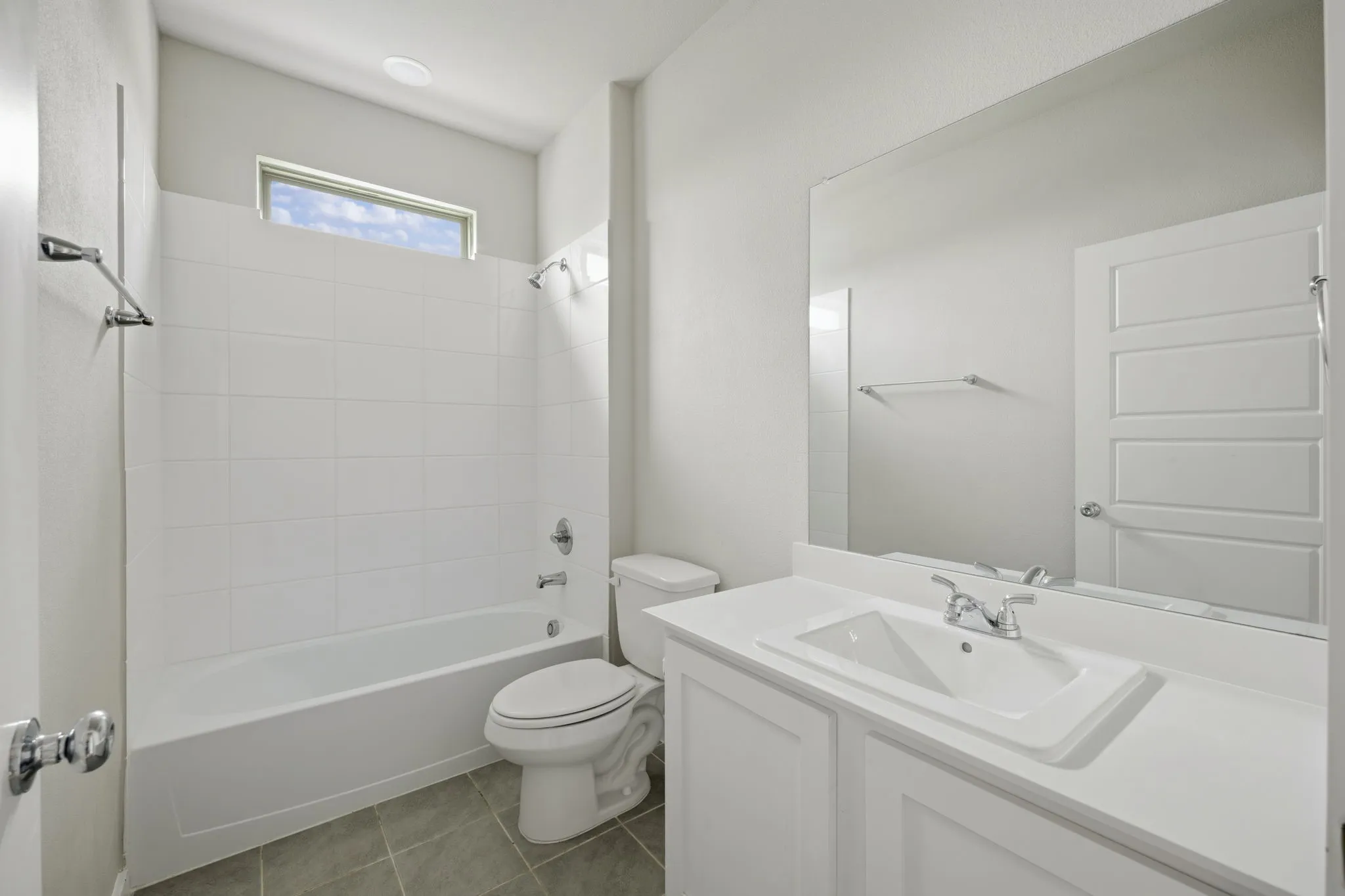 Bathroom featuring a white vanity with integrated sink, chrome faucet, and a large wall-mounted mirror