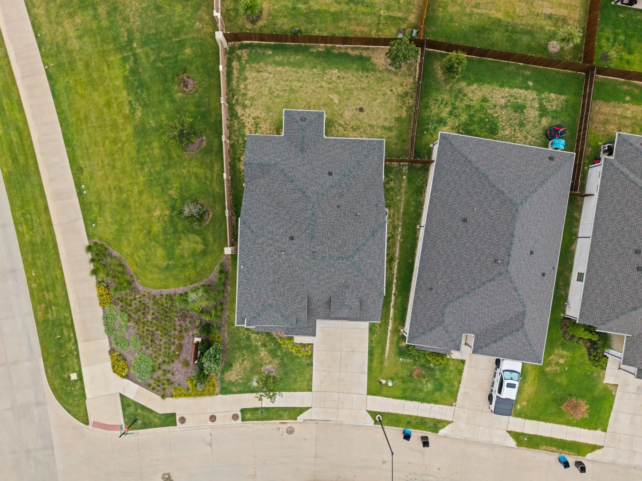 Gable roof design with asphalt shingles, concrete driveway, and established landscape beds