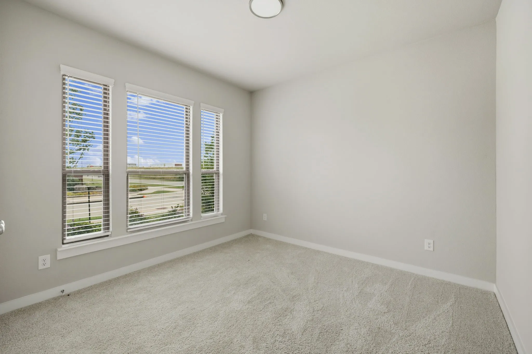 Bright room featuring three windows with horizontal blinds
