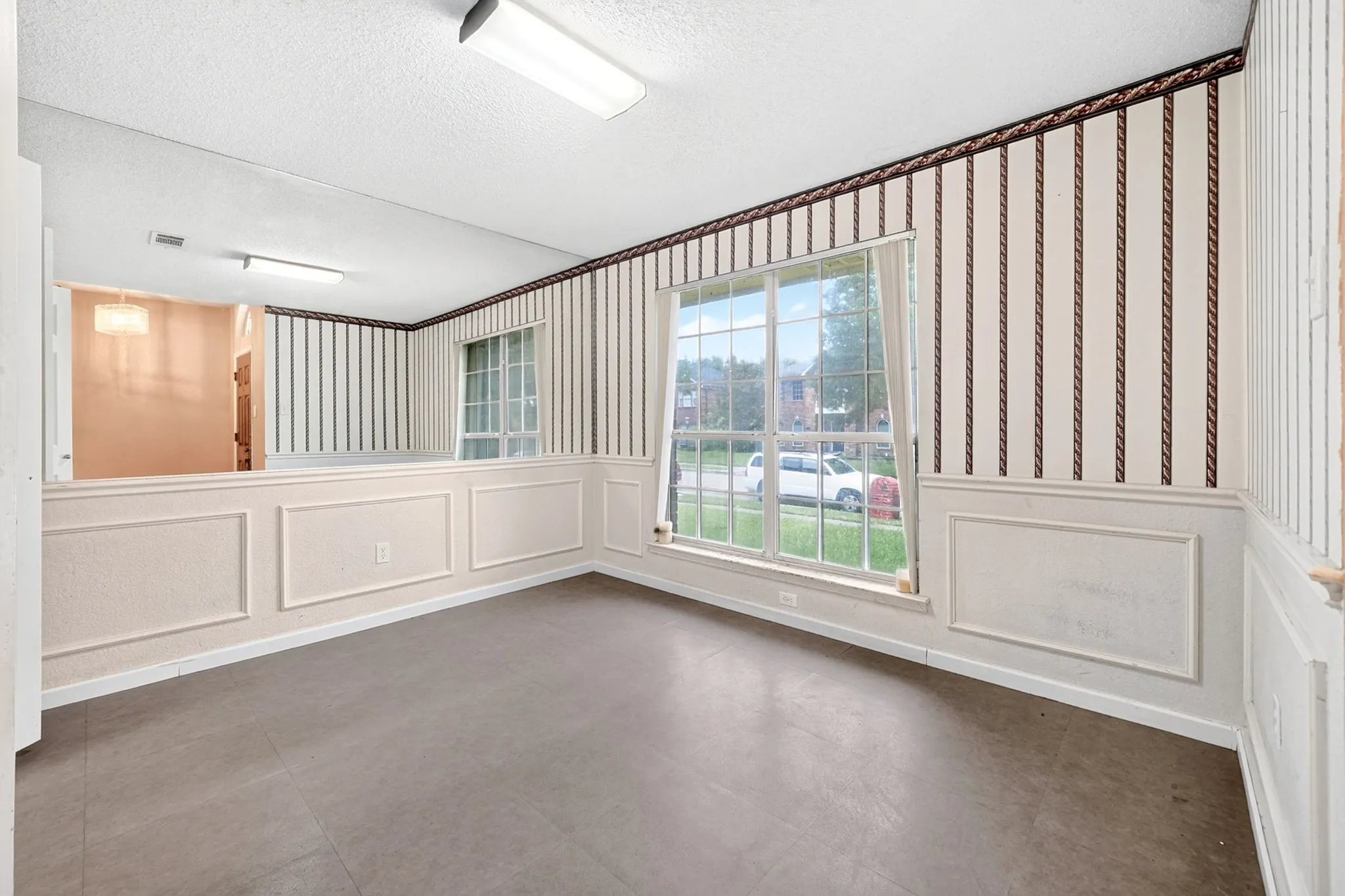 Interior space featuring wainscoting, striped wallpaper, a large window, and wood-finish flooring
