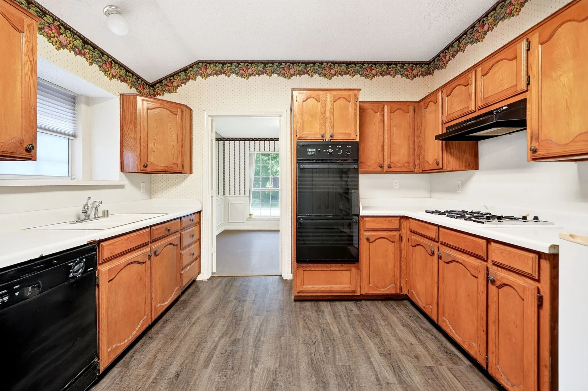 Kitchen with wood cabinetry, light-toned countertops, and wood-finish flooring