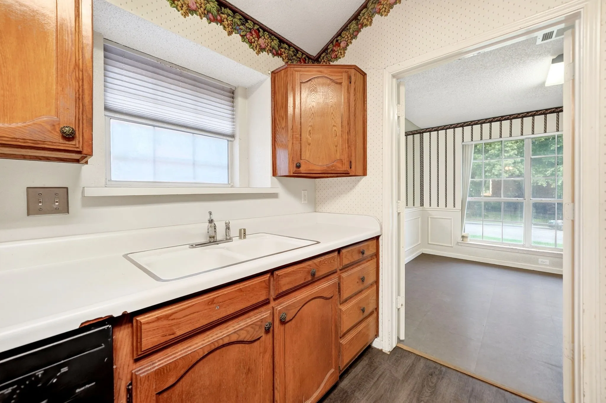 Kitchen sink area featuring a white countertop, classic wood cabinetry, and a double-basin sink with a chrome faucet