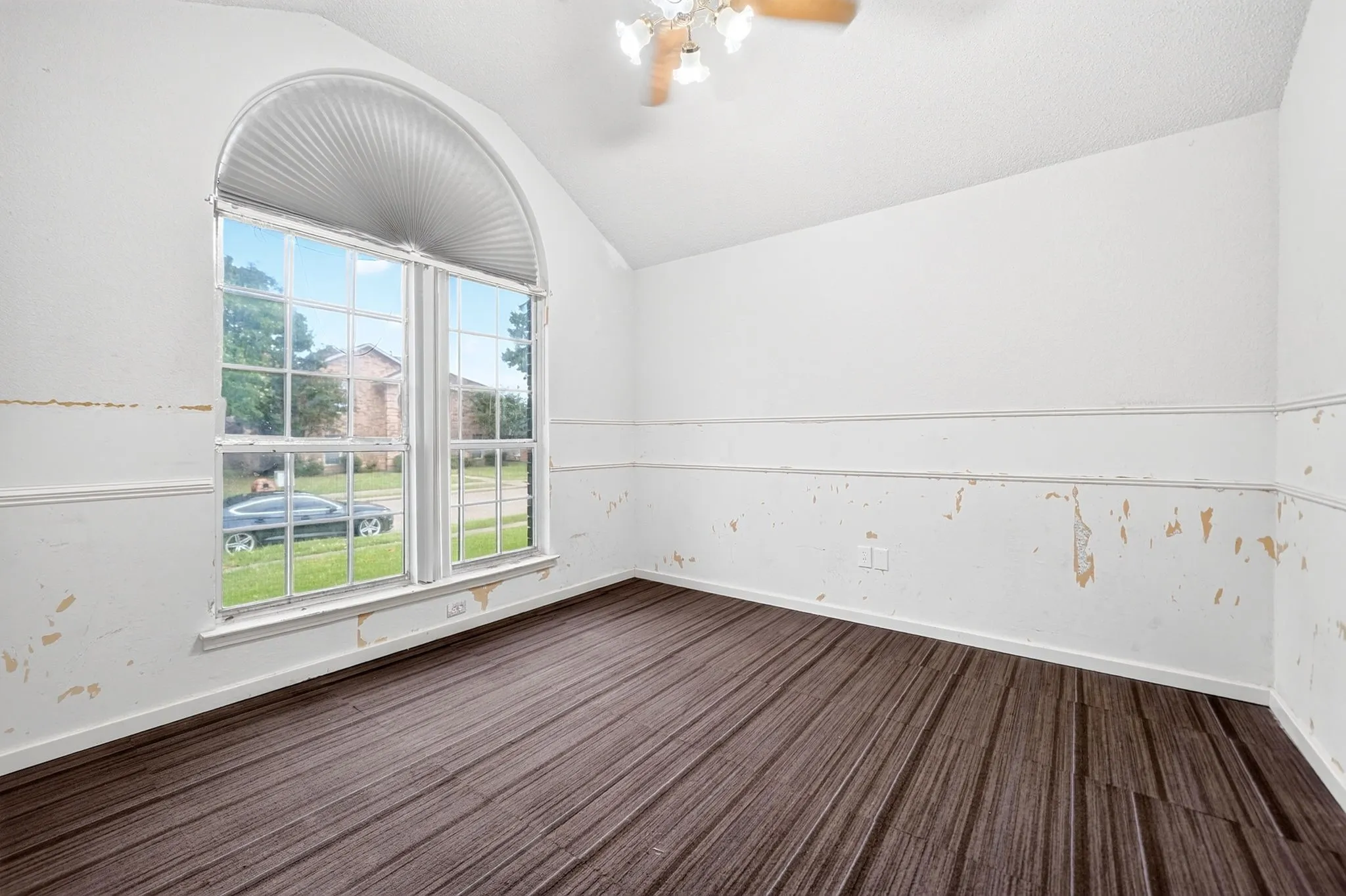 Room featuring an arched window with louvered blinds and wood-finish flooring