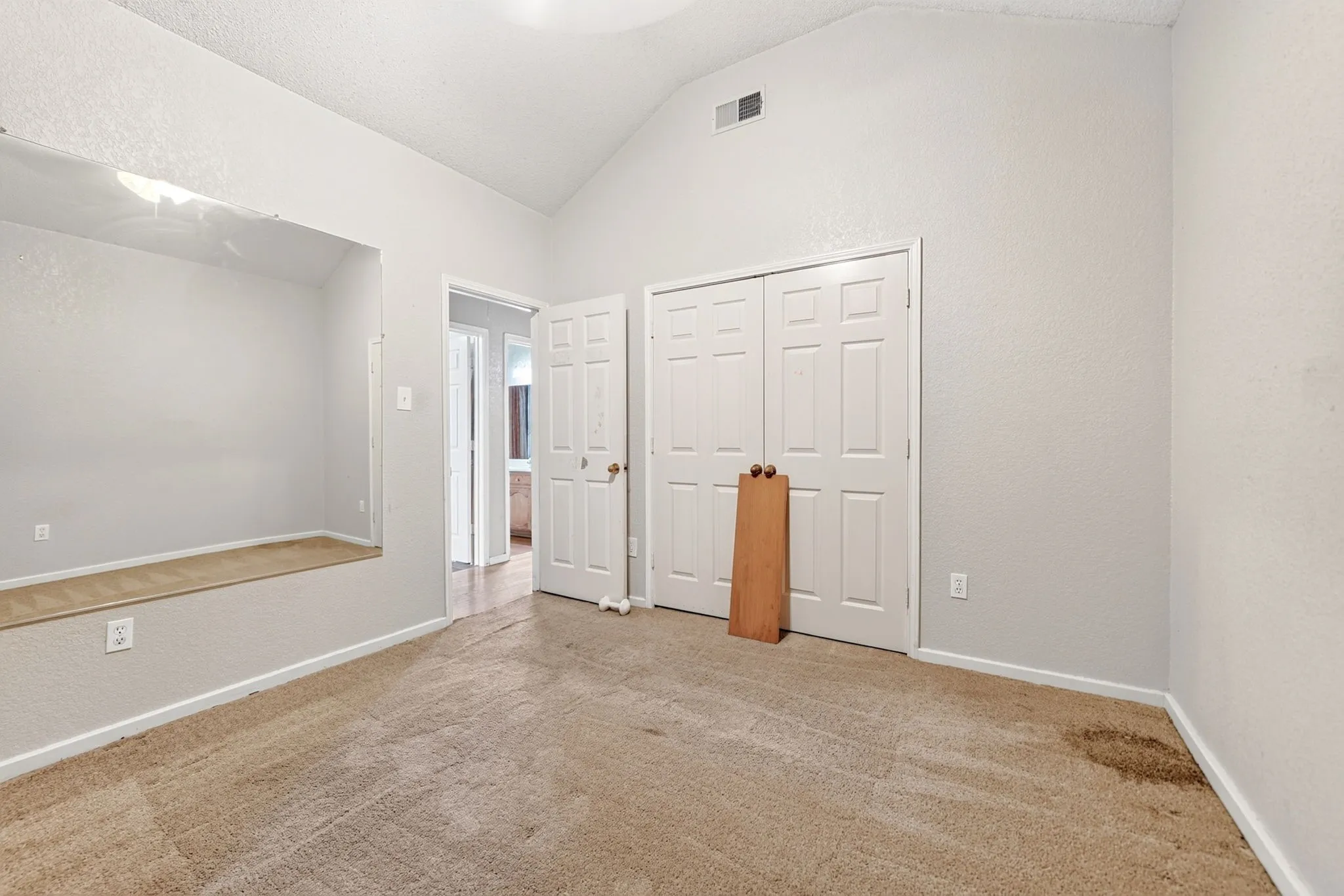 Interior space featuring a vaulted ceiling, neutral wall paint, and a built-in recessed niche with a light-colored wood-finish base