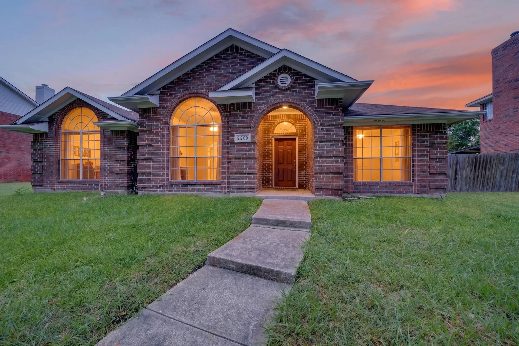 Brick facade residence featuring a covered front entry with an arched opening