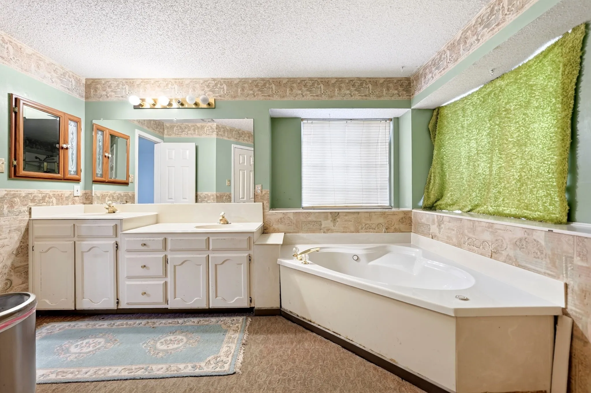 Expansive bathroom featuring a corner soaking tub, a dual vanity with white cabinetry, and a large wall-mounted mirror